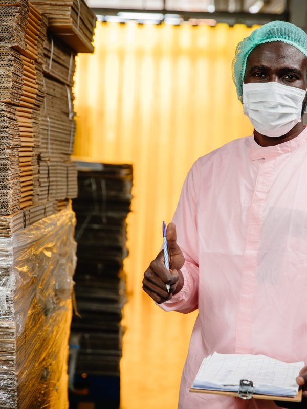 Black worker working in factory to check counting stock inventory in production warehouse standing thumbs up for good job and welfare. (Black worker working in factory to check counting stock inventory in production warehouse standing thumbs up for go